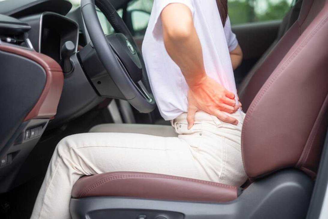 A person holding her back while sitting in a car
AI-generated content may be incorrect.